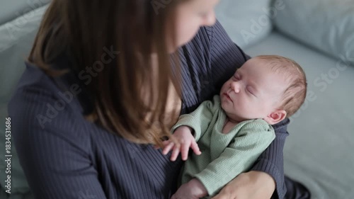A woman is caring for her baby. The mother is rocking the baby in her arms. The newborn is sleeping. A close-up of the baby in the woman's arms.