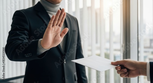 Professional businessman in a suit refuses an envelope or bribe with a stop gesture, emphasizing integrity and anti-corruption.