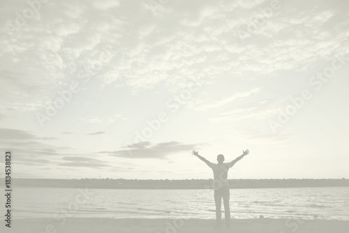 Silhouette of man with arms outstretched against cloudy sky on sunset near lake, Cloud Dancer color of the year 2026