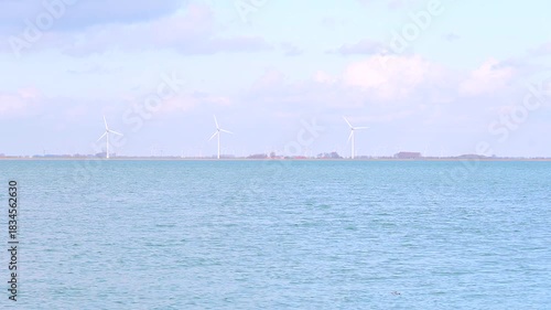 A row of wind turbines along the shoreline