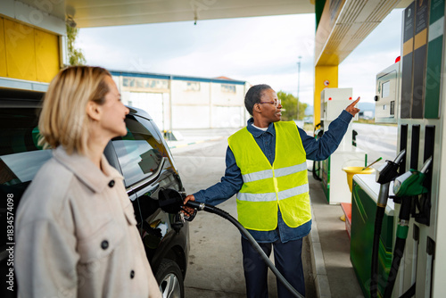Service worker assisting woman refueling car at gas station
