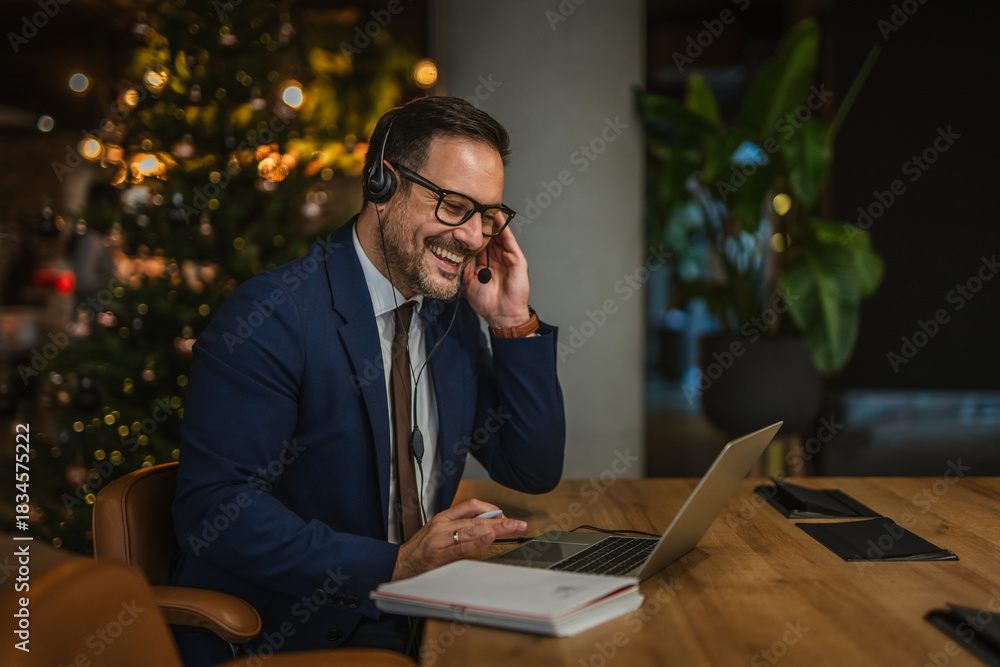 Fototapeta premium Businessman teleworking having a cheerful video call during christmas