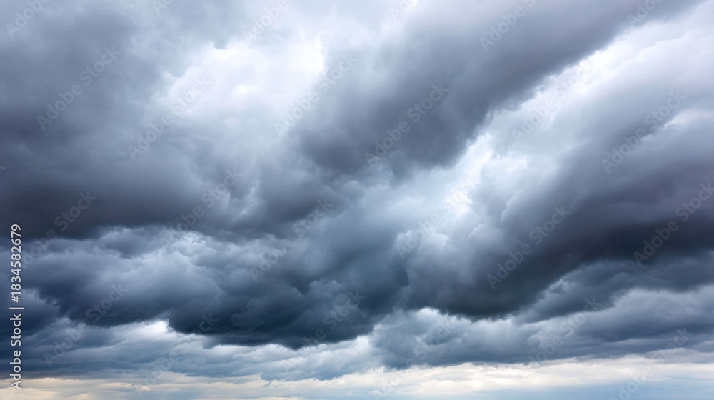 Obraz premium Dramatic Sky with Dark Storm Clouds and Bright Light Peeking Through on a Gloomy Day Over a Vast Open Landscape