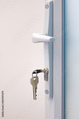 Door handle with key in lock on grey door. Concept of access, security and privacy.