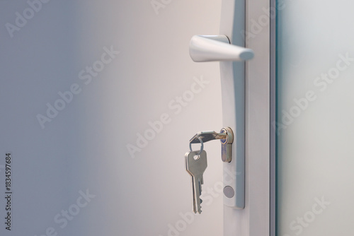 Door handle with key in lock on modern grey door. Close-up of a door handle and key in the lock, symbol of access, security and privacy.