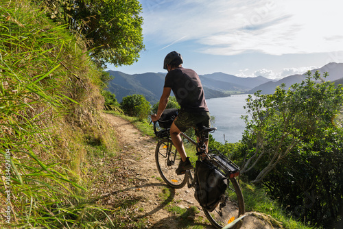 Cyclist bikepacking coastal Queen Charlotte Track in Marlborough Sounds, NZ