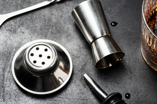 Cocktail Preparation Tools in Bar – Jigger, Pour Spout and Shaker Top on Dark Surface