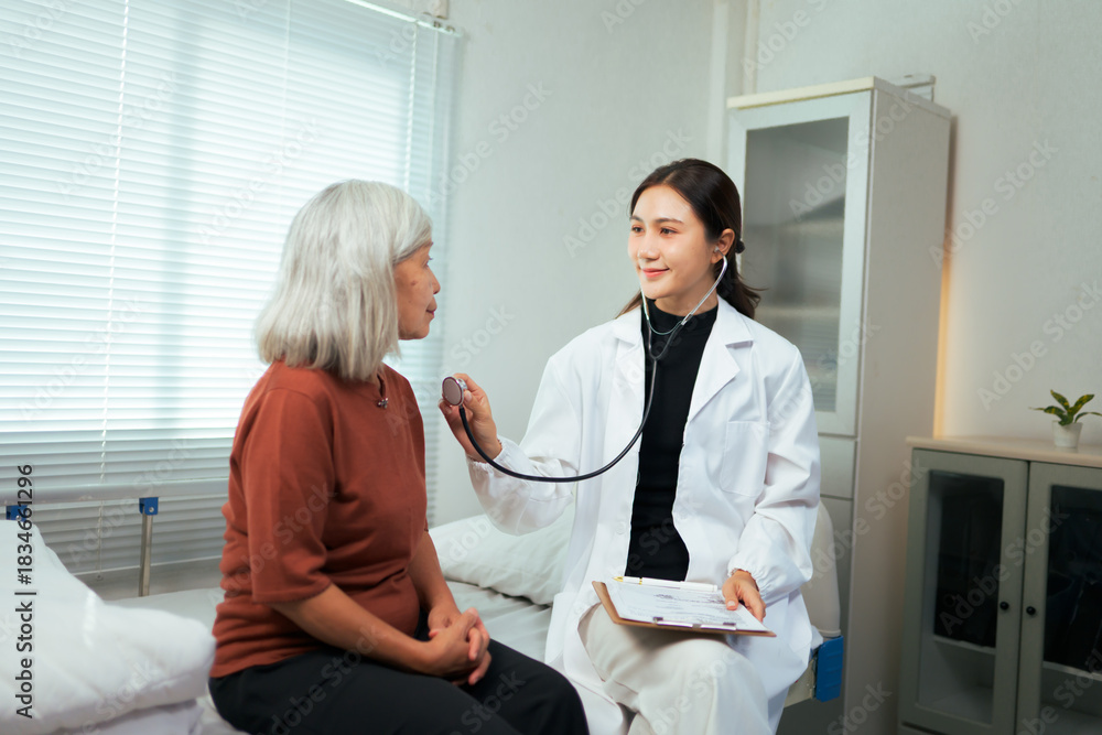Obraz premium Female doctor checking elderly patient's heartbeat with stethoscope