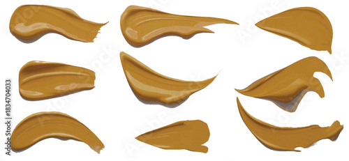 nine tan foundation smears makeup on a plain white background surface Golden Brown Paint Strokes Smooth Mustard Swatches for Artistic Backgrounds.
