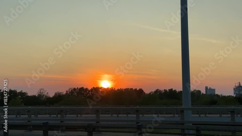 Sunset over horizon with power lines silhouetted against vibrant sky, showcasing gradual light change, camera pans to reveal expansive landscape and warm colors