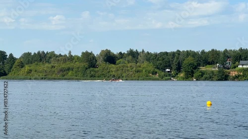 Boat glides smoothly across tranquil water, surrounded by lush greenery and distant shoreline, capturing serene nature scene with gradual camera zoom in