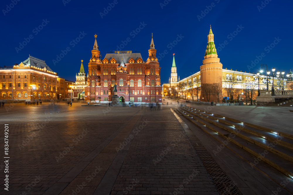 Fototapeta premium Moscow, Russia. Manezhnaya Square. Evening view of the building of the State Historical Museum and the towers of the Moscow Kremlin. Blurred figures of people in long exposure.