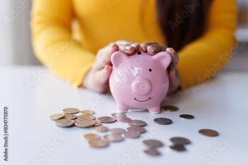 Saving money wealth concept, asian business woman hand putting coin into piggy for saving cost, cash finance planning to spend enough money on her income for save money, payment tax, investing.
