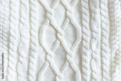 Close-up of white knitted wool sweater with cable pattern texture. Trendy color of 2026 year
