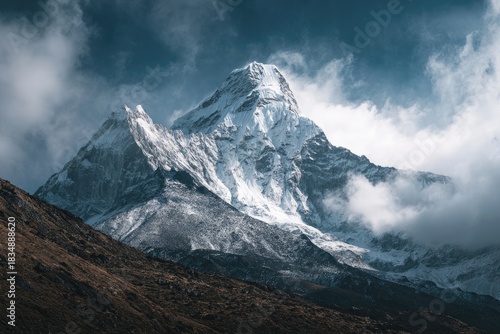 Wallpaper Mural Majestic snowy peak piercing through dramatic cloudscape. Rugged terrain in foreground Torontodigital.ca