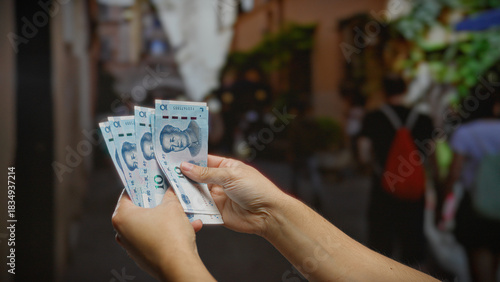 Canvastavla Man holding chinese yuan banknotes on an urban street, illustrating the concept of finance, currency exchange, and wealth in a busy city