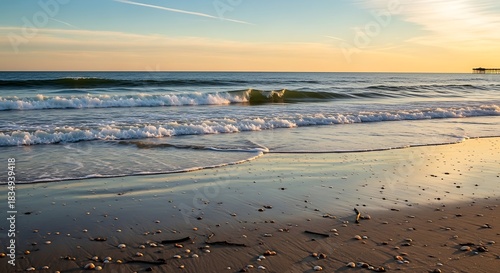 Gentle ocean waves wash ashore on a sandy beach at sunset.