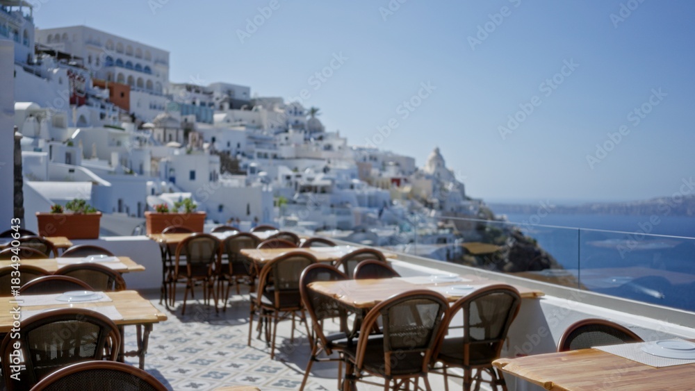 Fototapeta premium Rooftop cafe terrace with shallow blurred bokeh view of white coastal buildings and sea, soft defocused background; background backdrop copyspace calm.