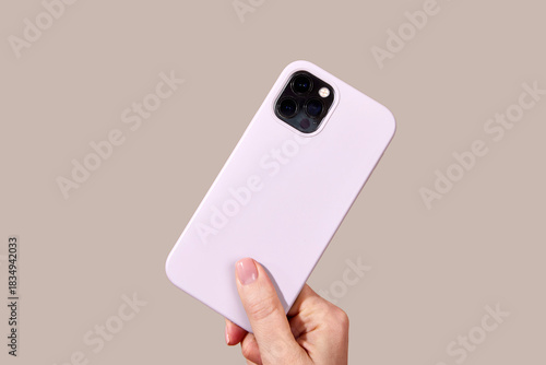 Hand holding sleek purple smartphone featuring multiple camera lenses against a worm gray background, highlighting modern mobile technology design elements Cloud Dancer color of 2026 year