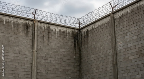 Contrasting confinement composition showcasing a wall topped with sharp barbed wire security