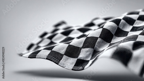 Close-up of a checkered flag waving in the wind against a soft gray background