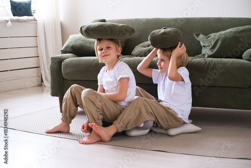 kids boys have fun with pillows, sitting on the living room floor
