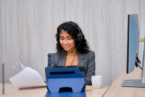 Mixed businesswoman meeting by online session with tablet at office desk and document paper.
