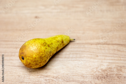 Ripe pear lying on a wooden surface. Pears are juicy fruits rich in minerals, fiber and easily digestible sugars. They support digestion, hydration and make a healthy snack.