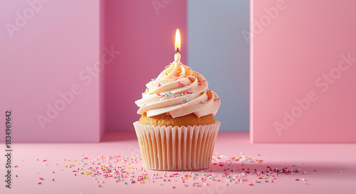 Pastel birthday cupcake with single lit candle and sprinkles on pink background, minimal party celebration dessert concept