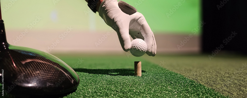 Fototapeta premium Golfer preparing to tee off at indoor driving range