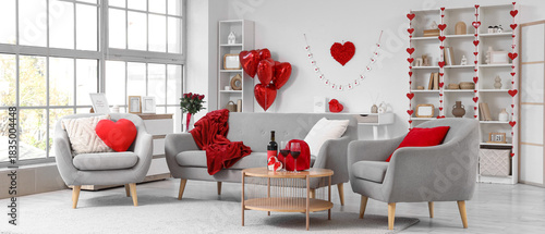 Interior of festive living room with grey sofa, wine, gifts and heart-shaped ...