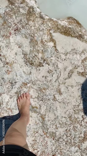 Woman's feet walking over the travertine at Pamukkale, the cotton castle and cotton hill, white travertine natural hot spring and, Hierapolis ruins site, Turkiye