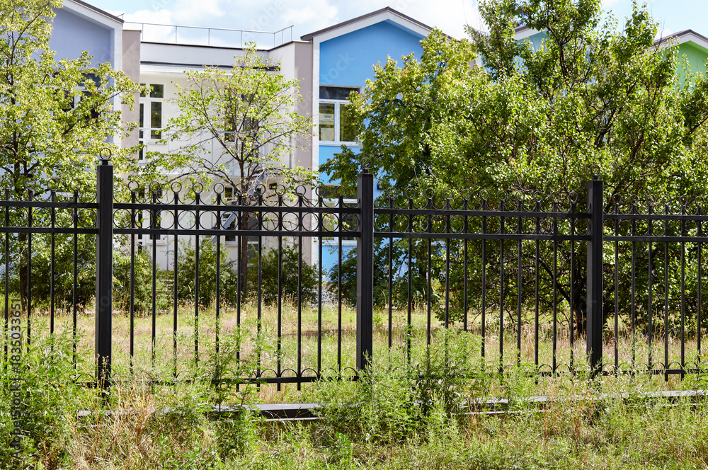 Fototapeta premium Metal fence in the city park. Decorative black iron guardrail for protection, close up