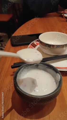 Thick camel yogurt served on the dessert bowl in slow motion. Vertical.