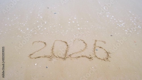 The inscription 2026 on the sand by the sea. Happy New Year.