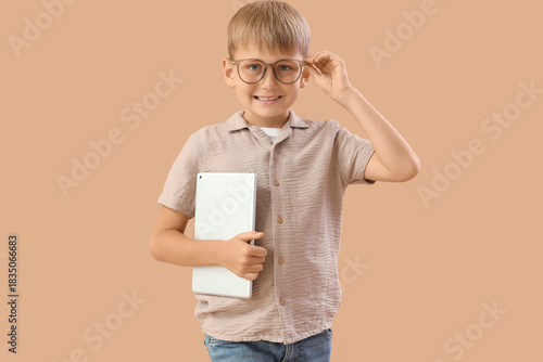 Little boy with laptop on beige background