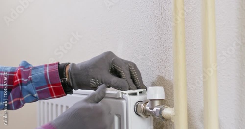Technician places protective cap on white wall radiator fitting aligning ears. Skilled plumber presses latch and locks cover verifying smooth movement