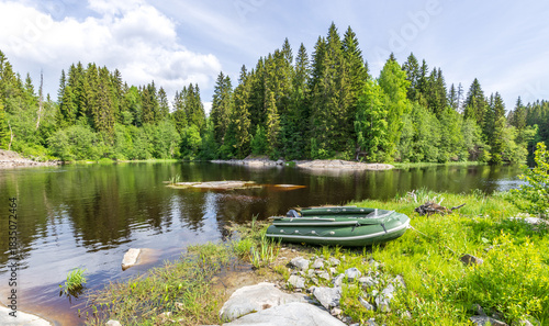 Green boat is sitting on the grass next to a lake