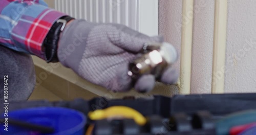 Technician tightens service plug on radiator outlet before checking seal. Male plumber hands set handle position preparing port for new valve installation