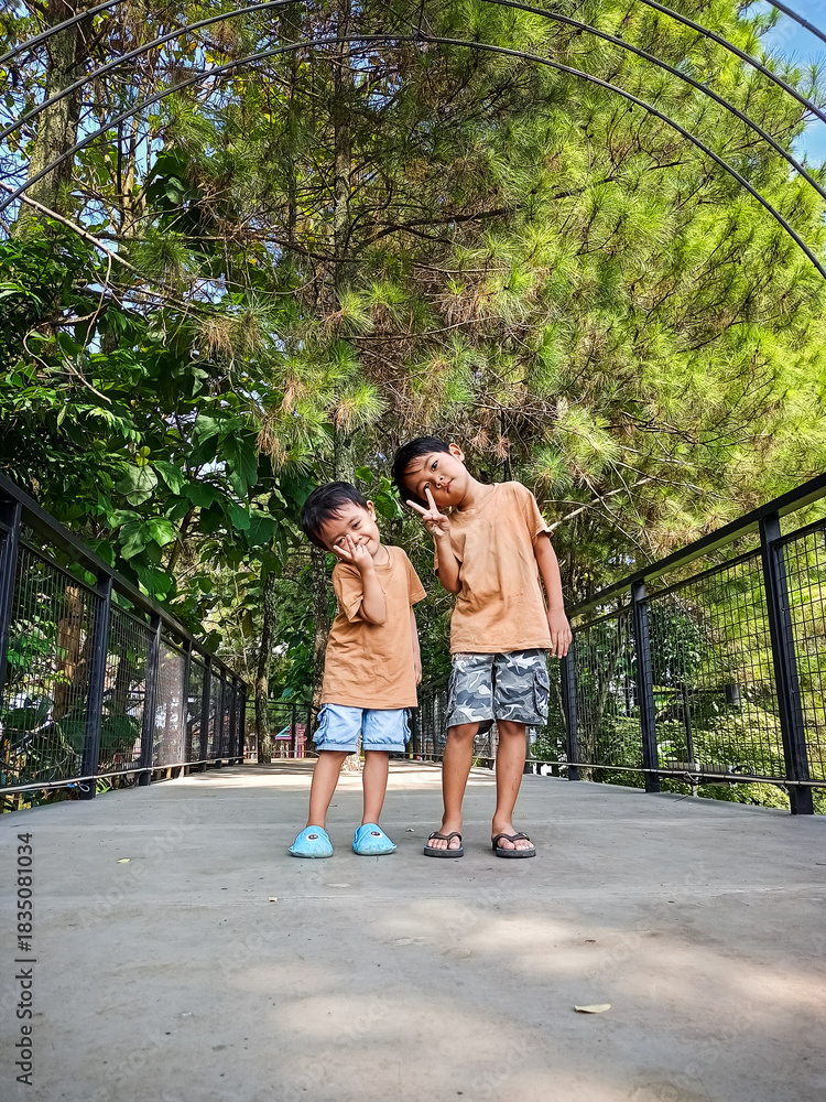 Obraz premium Playing with siblings in the park taking photos on a bridge