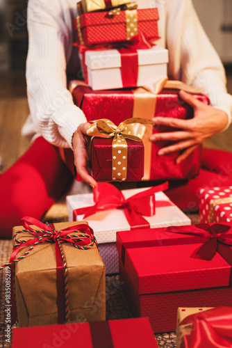 Warm red toned image with female person holding wrapped gift boxes.