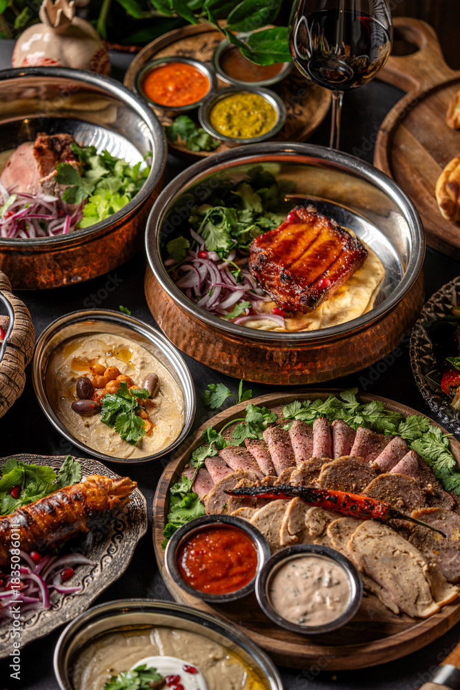 Fototapeta premium Assorted rustic meat dishes with sauces and hummus