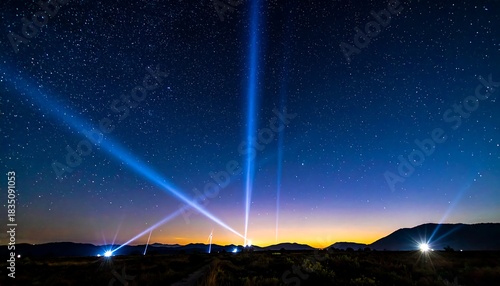 Brilliant blue beams shoot skyward amid a starry expanse over a dark landscape and distant rolling hills