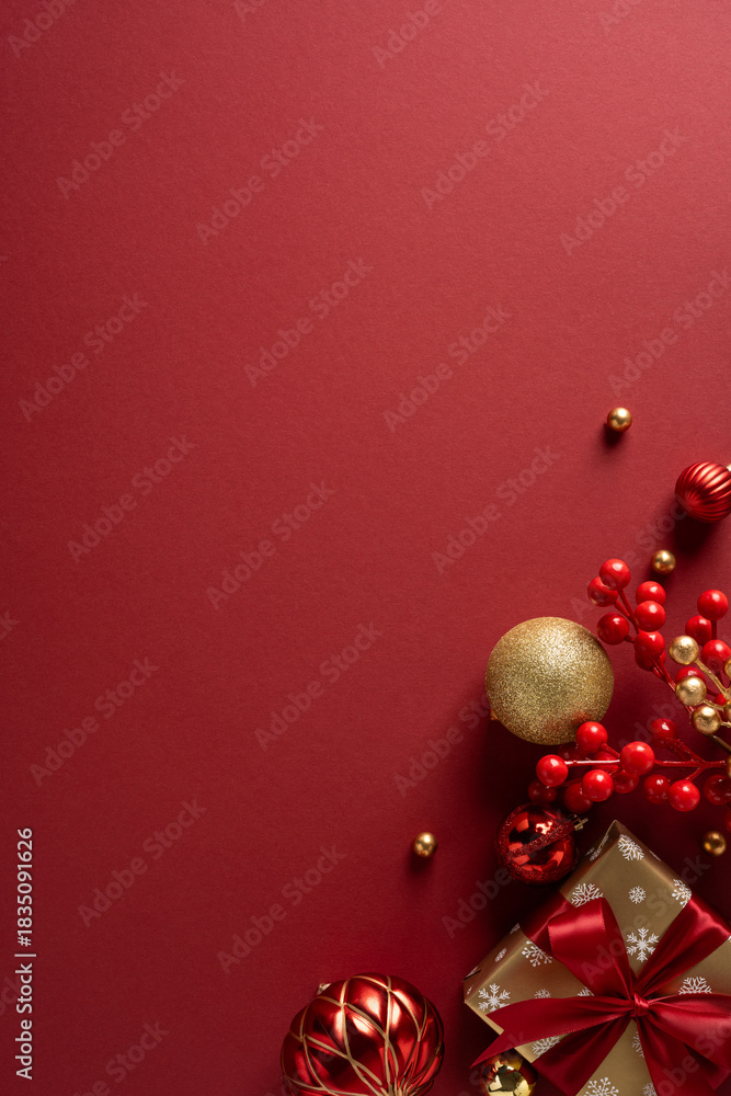 Obraz premium A vertical rich red holiday scene with glittering ornaments, gold accents, a wrapped gift and red berry clusters. Ideal for Christmas and New Year greetings