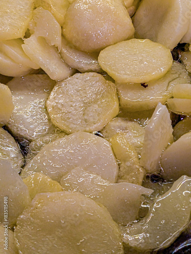 Detailed view of potato slices cooking in hot water or oil, creating a rich texture.