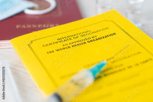 international certificate of vaccination a document for recording the vaccines made. the document is a yellow color. passport of a foreign citizen and a syringe on table. concept of safe travel.