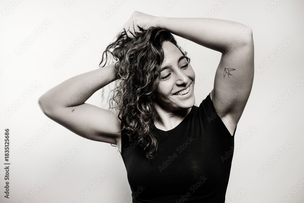 Fototapeta premium Happy woman with curly hair smiling in black and white