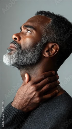Middle aged adult male with grey facial hair and a contemplative expression.