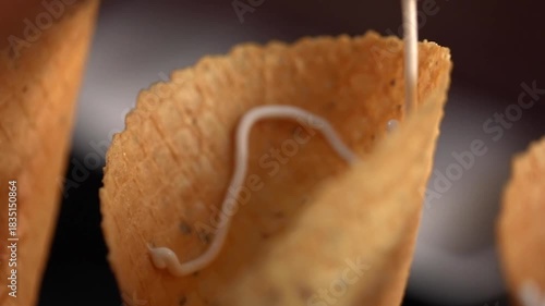 Filling waffle cone with cream. Preparing waffle cone with filling.