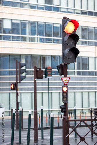 A vibrant red traffic light stands out at a busy urban intersection, highlighting the constant movement of city life while designed with a modern aesthetic.